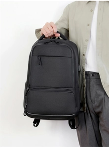 Close-up of a model holding a black waterproof oxford business backpack with multiple pockets