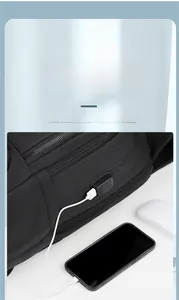 Detail of side USB charging port on black business backpack connected to a smartphone