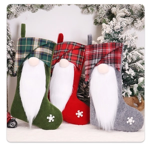 Trois chaussettes de Noël gnomes avec motifs à carreaux et flocons sur aiguilles de pin
