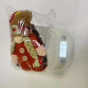 Detailed view of long-legged Thanksgiving turkey gnome doll on weight scale in packaging