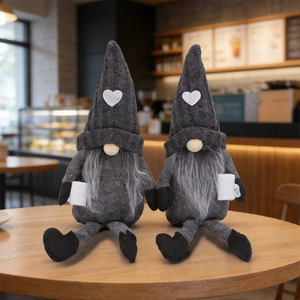 Close-up of two knitted grey Christmas gnomes with heart hats sitting on a wooden table