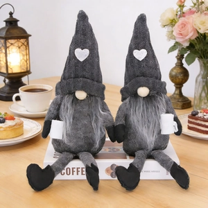 Pair of gray knitted coffee gnomes with heart hats on a cozy wooden table set