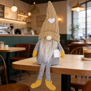 Cozy Swedish gnome plush with heart knit hat holding a mini coffee mug on a table