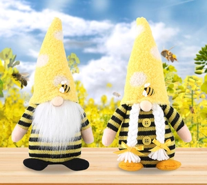Close-up of knit bee gnomes with striped bodies and fuzzy yellow hats on wood