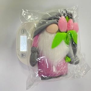 Gnome plush toy with pink tulips being weighed on a digital scale showing 52.8g
