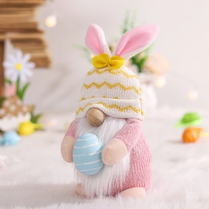 Detail of Easter gnome plush with pink rabbit ears holding a blue striped egg decor