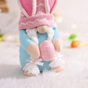 Detail of Easter gnome figurine with pink bunny ears holding a striped egg on soft fur