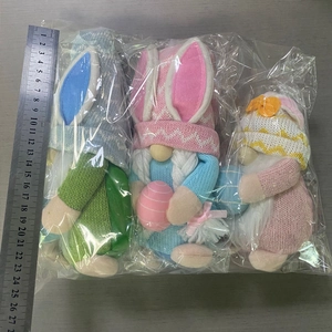 Detailed view of three knitted Easter bunny gnomes in packaging with ruler for scale