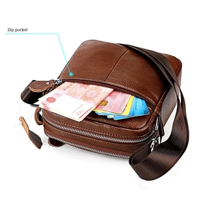 Détail du sac bandoulière en cuir marron montrant les poches zippées et porte-cartes