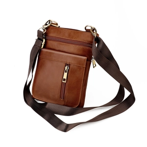 Detail view of brown genuine leather messenger bag with zipper pockets and nylon strap