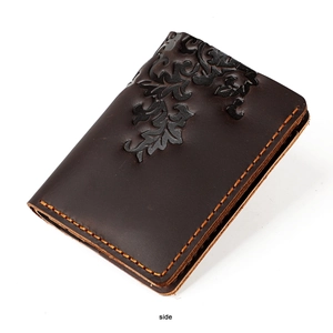 Detail of dark brown leather card holder featuring embossed floral motifs and contrast stitching