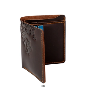 Detail of vintage brown leather wallet with embossed floral patterns and hand-stitched edges