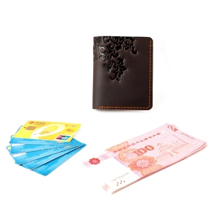 Detail of dark brown leather wallet with vintage floral embossing and orange hand-stitching