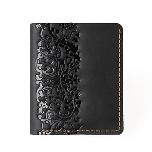 Detail of vintage black leather wallet showing floral embossing and orange contrast stitching