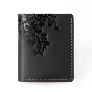 Macro shot of black crazy horse leather wallet with orange stitching and vintage embossing