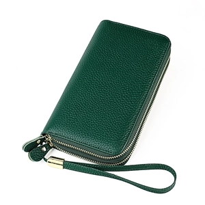 Detailed macro view of dark green pebbled leather texture with gold zipper hardware