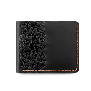 Detailed macro view of black leather wallet with floral embossing and contrast stitching