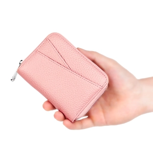 Pink lychee grain leather card holder with zipper closure held in hand for scale