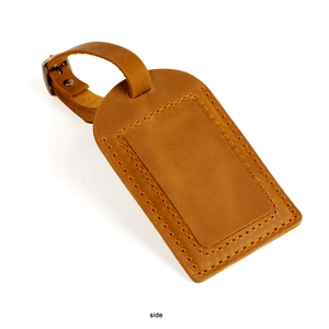 Side view of dark brown crazy horse leather luggage tag with orange stitching and brass buckle