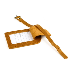 Detail view of brown leather luggage tag with adjustable strap and white contact info card