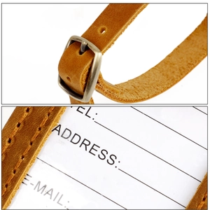 Macro detail of crazy horse leather luggage tag with bronze buckle and stitched edges