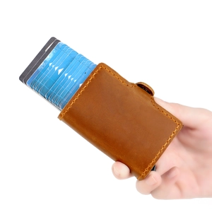 Détail du portefeuille en cuir marron montrant le porte-carte automatique tenu à la main