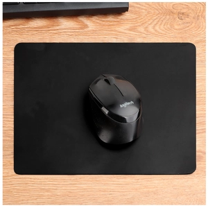 Primer plano de un tapete de escritorio de cuero negro sobre una mesa de madera