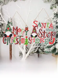Detail view of plaid Merry Christmas and Santa Stop Here wooden ornaments on white branches