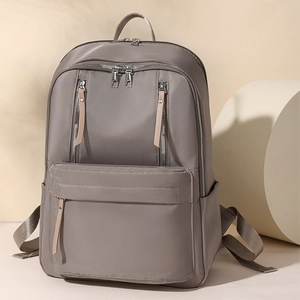 Detail view of grey nylon backpack with metallic zippers and beige leather pulls