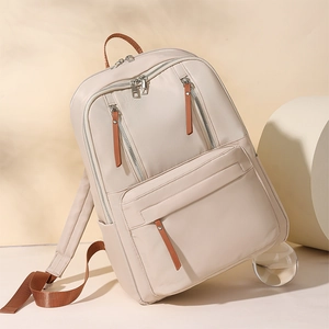 Detail view of large capacity beige backpack with multiple brown zipper pockets