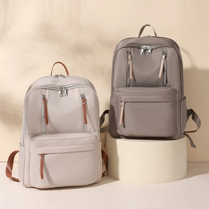 Detail view of large capacity nylon backpacks in beige and taupe on a display stand