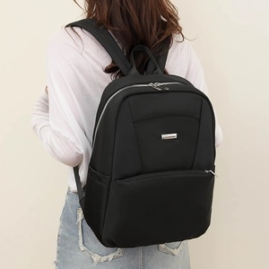 Rear view of black waterproof nylon backpack on model with silver metal zipper details