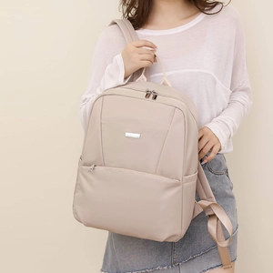 Close-up of beige waterproof nylon backpack with metal logo and smooth zipper detail