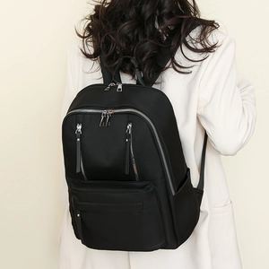 Back view of a model wearing a sleek black large capacity nylon backpack for travel