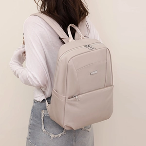 Detailed back view of light beige nylon backpack featuring wide straps and metal logo plate