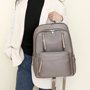 Detail view of large capacity grey-brown nylon backpack with metallic zippers and pockets