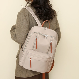 Woman in wool blazer wearing a khaki nylon backpack with multiple zipper pockets