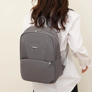Close-up of minimalist dark grey backpack with silver metal bar and smooth zipper detail