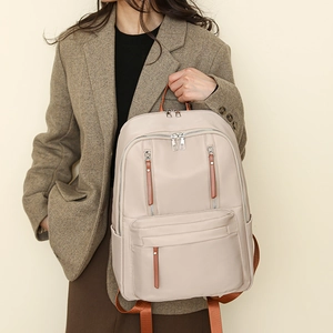 Detailed side view of a beige minimalist backpack featuring brown zipper pulls for travel