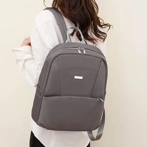 Detail of dark grey waterproof nylon backpack with a silver logo plate for daily commute
