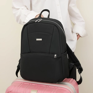 Detail of black nylon backpack with multi-zipper compartments on a pink suitcase