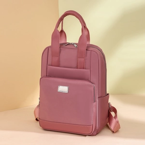 Détail d'un sac à dos en nylon rose avec plusieurs poches zippées et garniture en métal