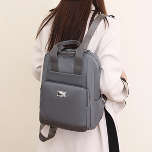 Vue arrière d'un mannequin portant un sac à dos en nylon bleu gris avec sangles marron
