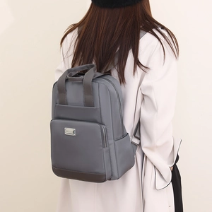 Sac à dos gris en nylon avec fermetures éclair et poche latérale vu de côté sur modèle