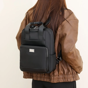 Vue arrière d'un mannequin portant le sac à dos noir en nylon avec détails argentés