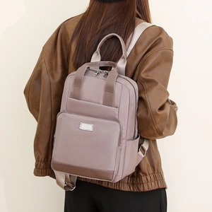 Vue arrière d'un grand sac à dos en nylon rose gris porté par un mannequin en studio
