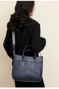 Détail d'un sac à main bleu marine rétro avec bandoulière rayée et texture plissée