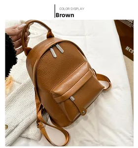 Detail view of brown pebbled PU leather backpack showing zip pocket and top handle