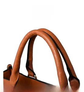 Détail des poignées rondes en cuir marron avec ferrures dorées sur un sac à main