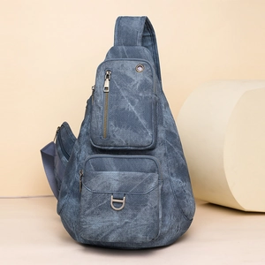 Detail view of washed blue denim texture with multi-layer zipper pockets and D-ring